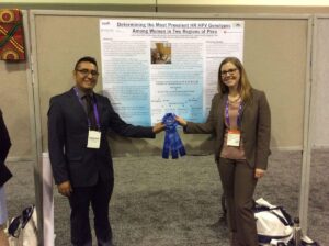 Two people standing in front of their research poster with the award ribbon for winning.