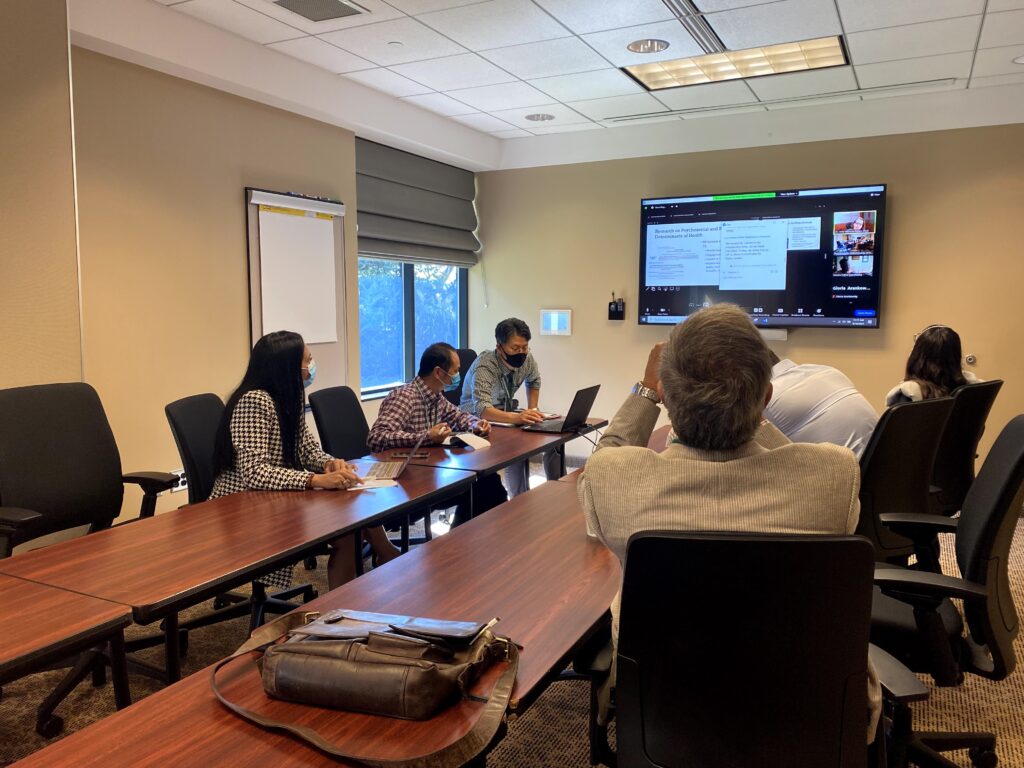 A photo from the 2021 ERCA conference of a group of people in a hybrid "breakout room." A group of six people in person along with a group on zoom