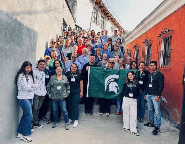 A group of people on the stairs in an alley holding up a Spartan flag