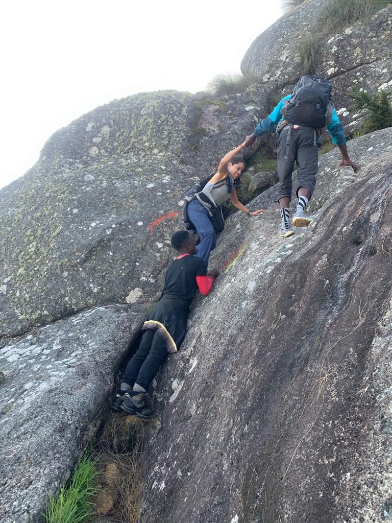 Three people scaling a steep mountain