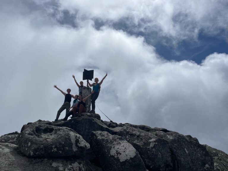 A group of people at the top of a mountain with their hands out