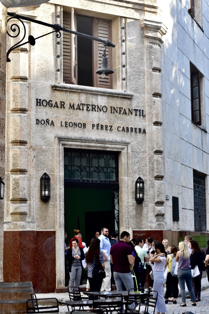 The front of the Hogar Materno Infantil buliding, a beige exterior with people by the entrance