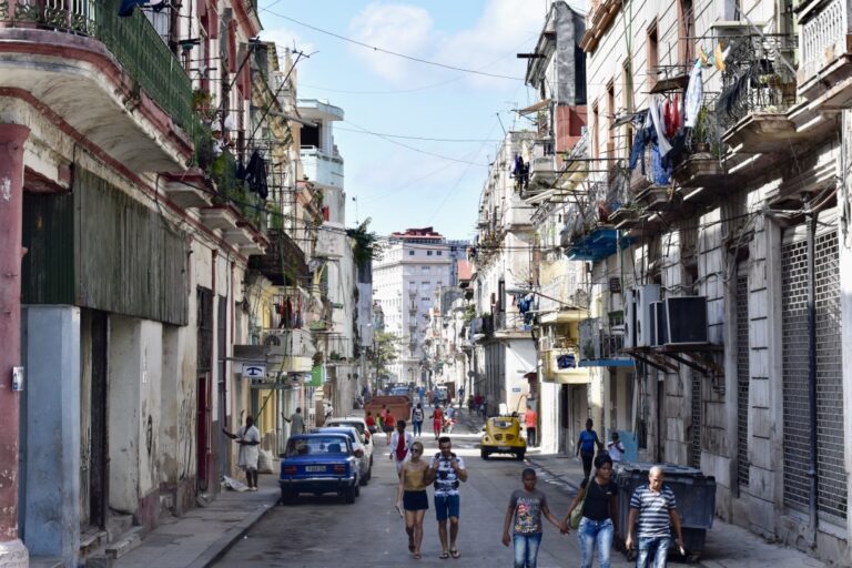 A street in Cuba with people and cars on the road