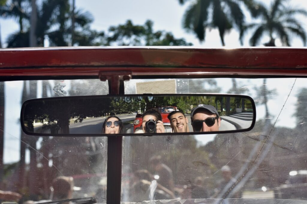 4 peoples' heads in the rearview mirror of a car