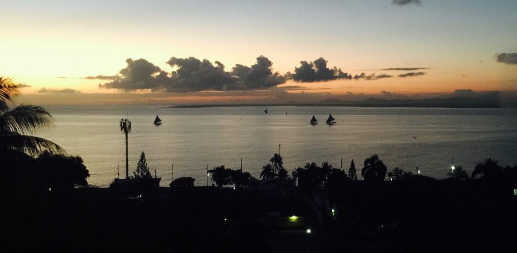 View of the water with some sailboats on it at sunset