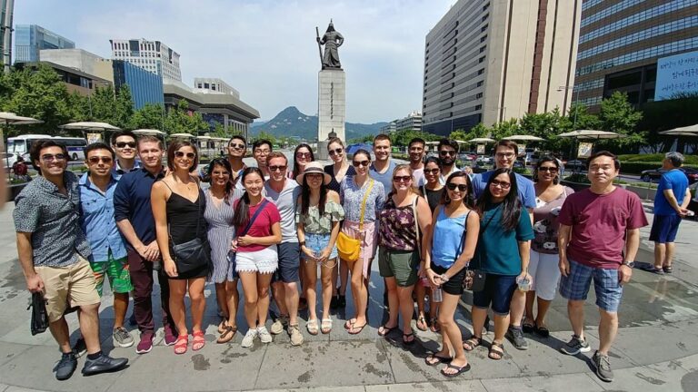 Group of people touring the city, standing in front of a statue.