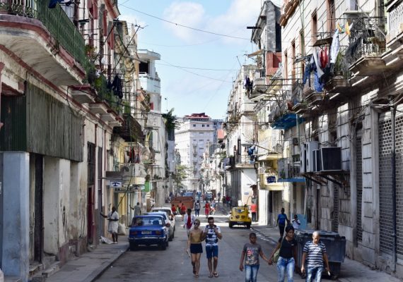 A street in Cuba with people and cars on the road